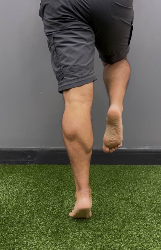 distance runner performing single leg calf raise during achilles tendon rehabilitation