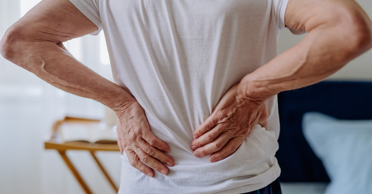 Person Holding Lower Back With Pain Radiating Down Leg
